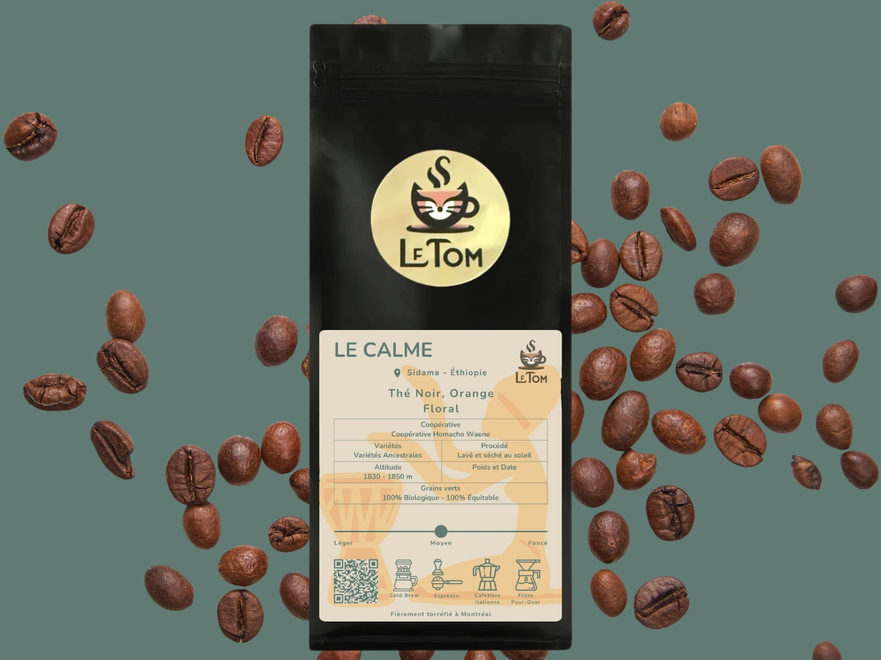 Sac de café Le Tom Café Le Calme entouré de grains de café sur fond vert sauge. Emballage noir avec logo circulaire doré Le Tom et étiquette beige avec graphique orange subtil. L'étiquette indique l'origine éthiopienne avec des variétés ancestrales cultivées à 1830-1850m d'altitude. Certifications 100% biologique, 100% commerce équitable et torréfaction moyenne. Les icônes montrent l'adéquation pour cold brew, espresso, cafetière moka et versement manuel.