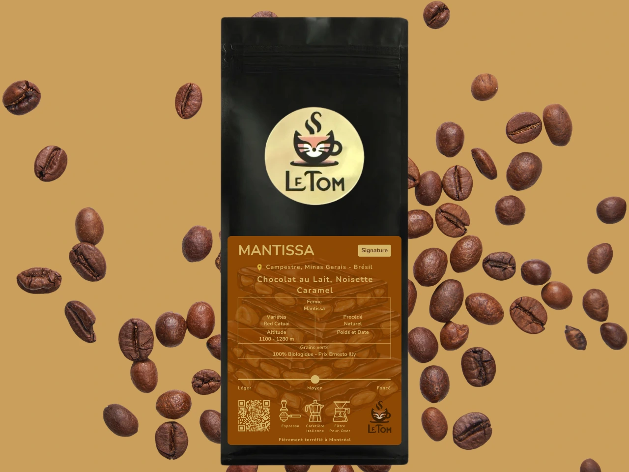 Le Tom Café Mantissa coffee bag surrounded by scattered whole coffee beans against a warm beige background. Black package with gold circular Le Tom cat logo and brown label indicating Brazilian origin. Label specifies flavor notes of milk chocolate, hazelnut, and caramel with 100% organic certification, Rainforest Alliance certification, and medium roast marker between Léger and Foncé. Suitable for espresso, moka pot, and pour-over brewing.